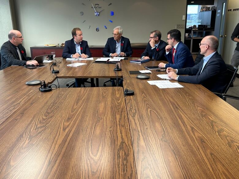 Six men sit at a table