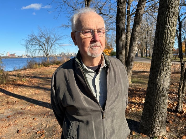 A man stands in a park in autumn.