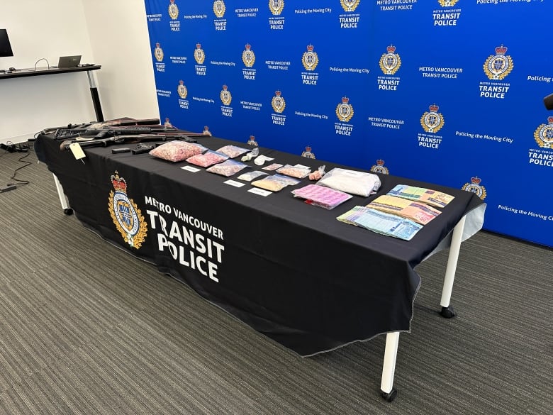 a table full of items seized by police in drug bust. this includes cash, drugs, guns