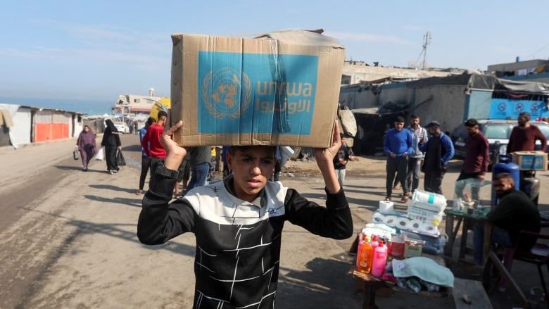 A young boy carries a box over his head.