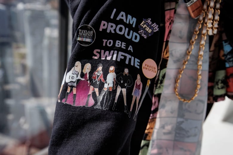 Person shows a sweatshirt sleeve that reads: I am proud to be a Swiftie.