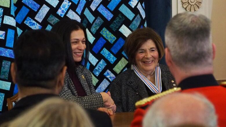 A woman shakes hand with another woman. 