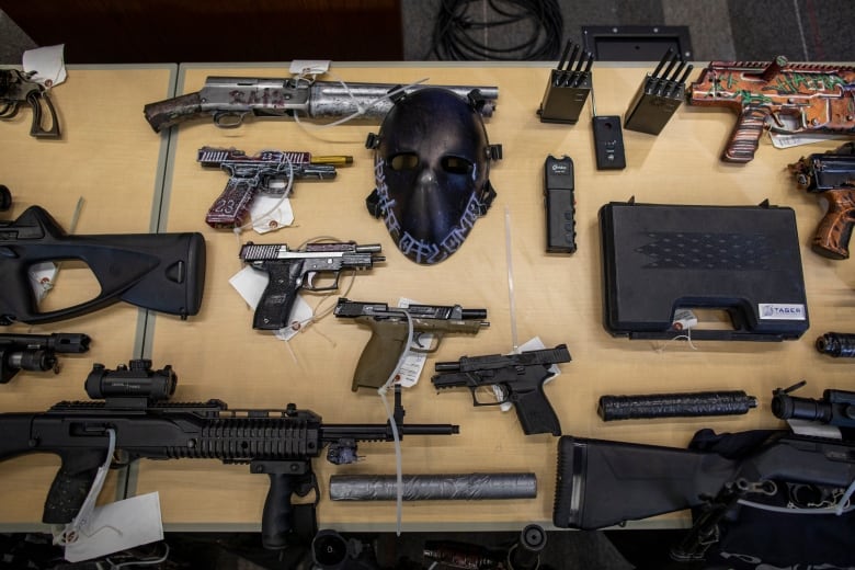 A small arsenal of guns is displayed on a table.