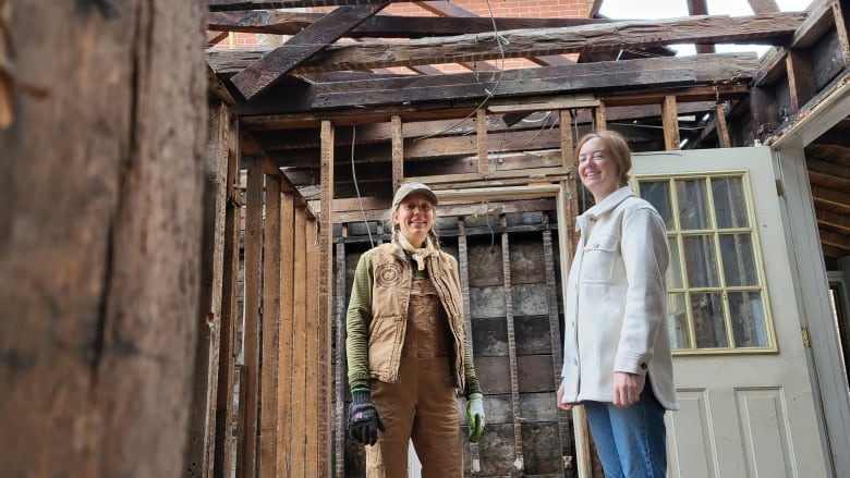 Two women in the wood frame of a house