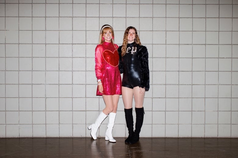 Two Swifties standing against a tiled wall for a portrait.