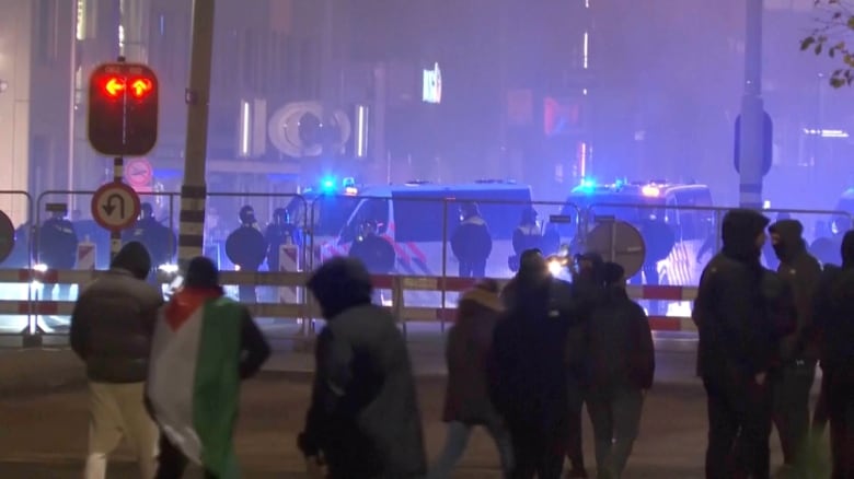 A group of people walk toward a police line during a protest.