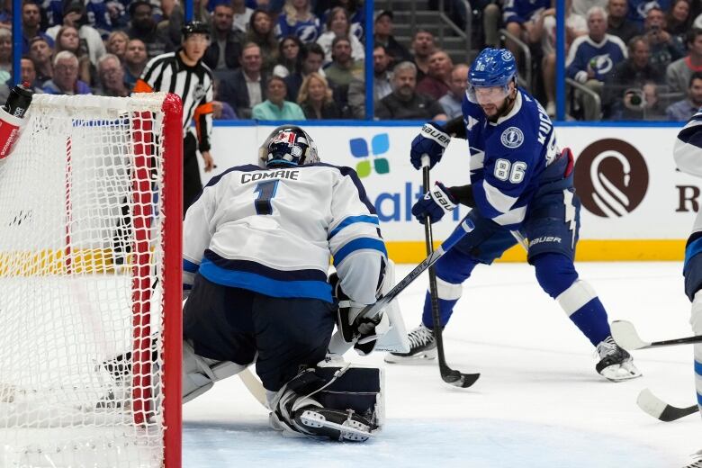 A player in blue shoots on a goalie in white.