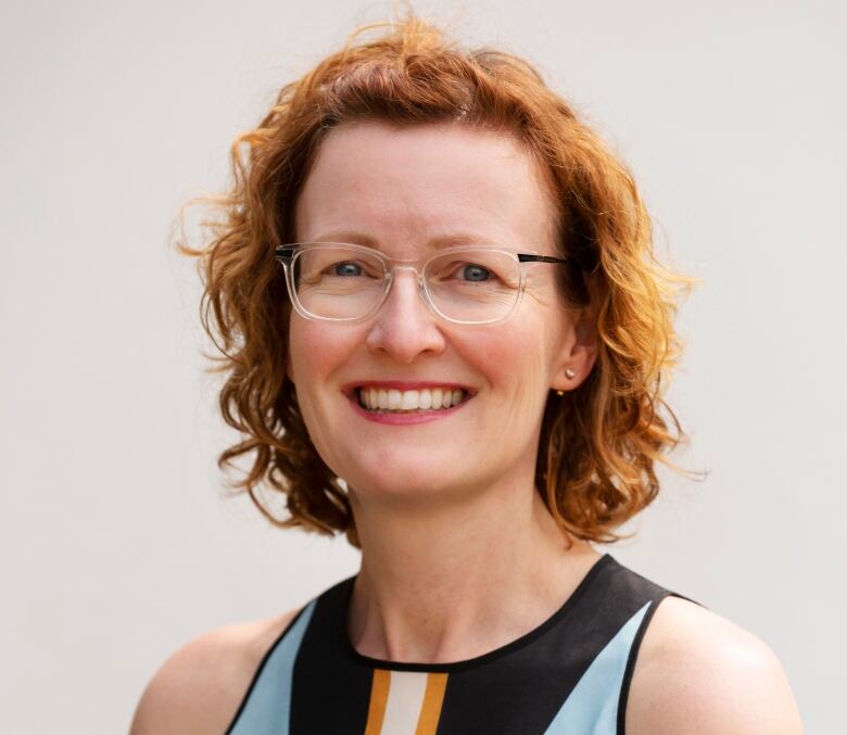 A woman with auburn hair wearing glasses.