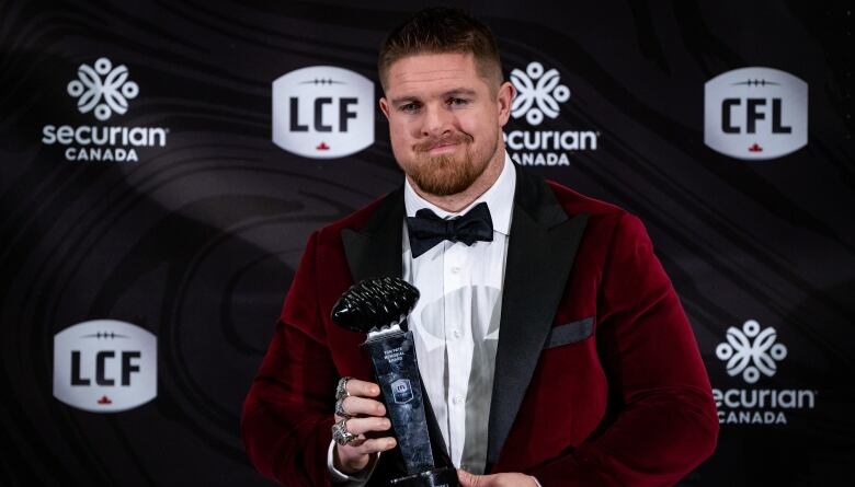 A man holds up a trophy.