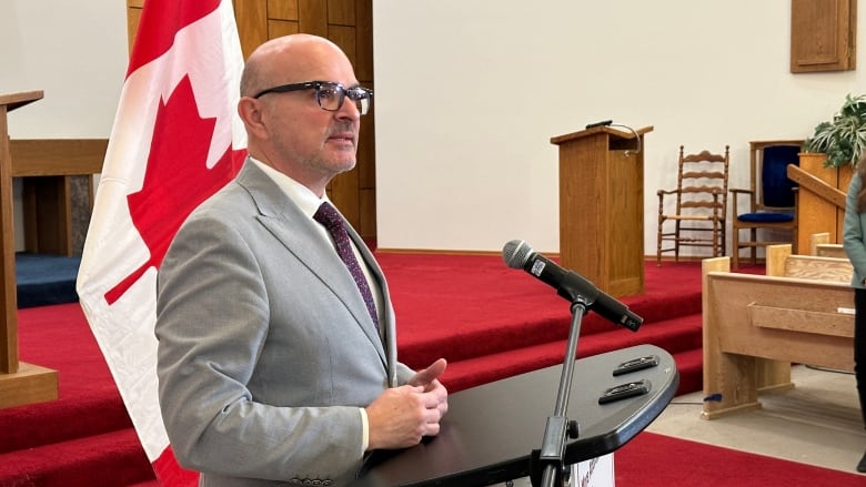 A man in a suit stands at a podium