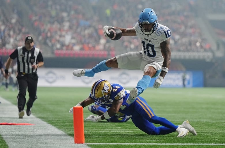 A football player leaps into the end zone.