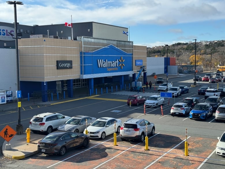 The parking lot and front of a Walmart store. A Nova Scotia and Canadian flag on top of the building are at half mast. 