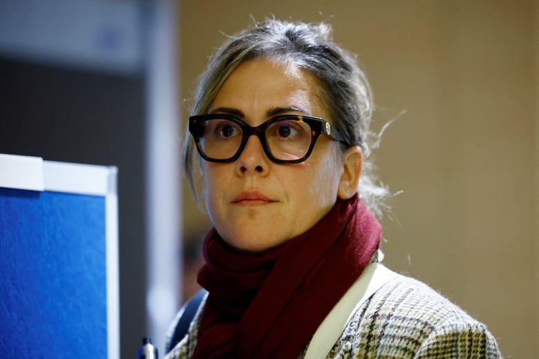 A photo of a woman wearing a coat and thick glasses