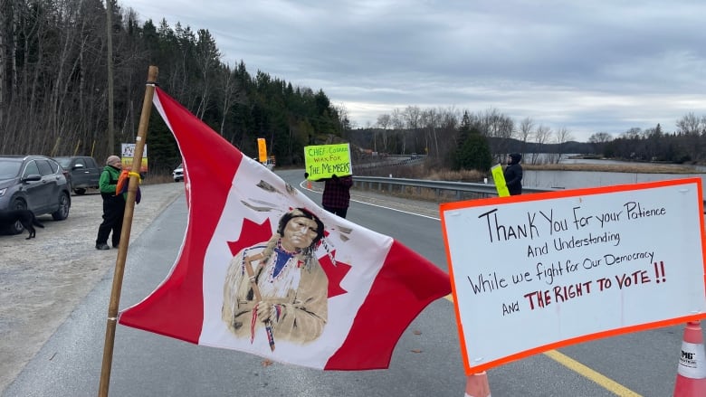 A sign with protestors and a flag.