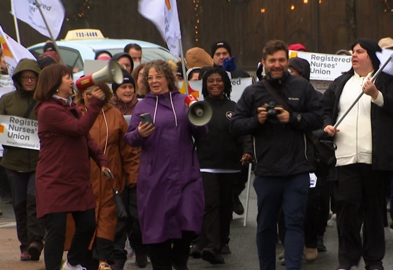 A crowd of people walk with flags and megaphones.