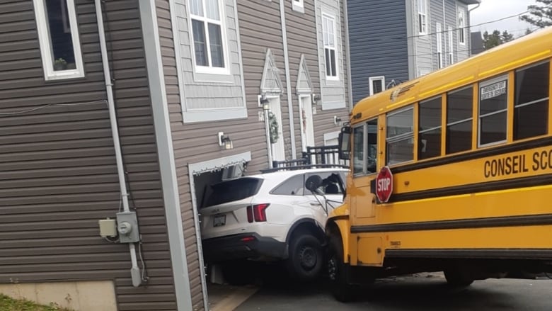 A school bus is seen crashed into a white car and a home. 