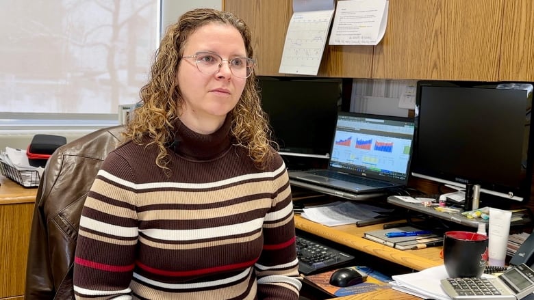 A woman sits behind her desk in an office.