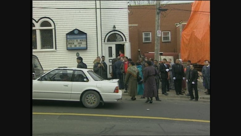 A crowd of people in winter jackets standing outside a church