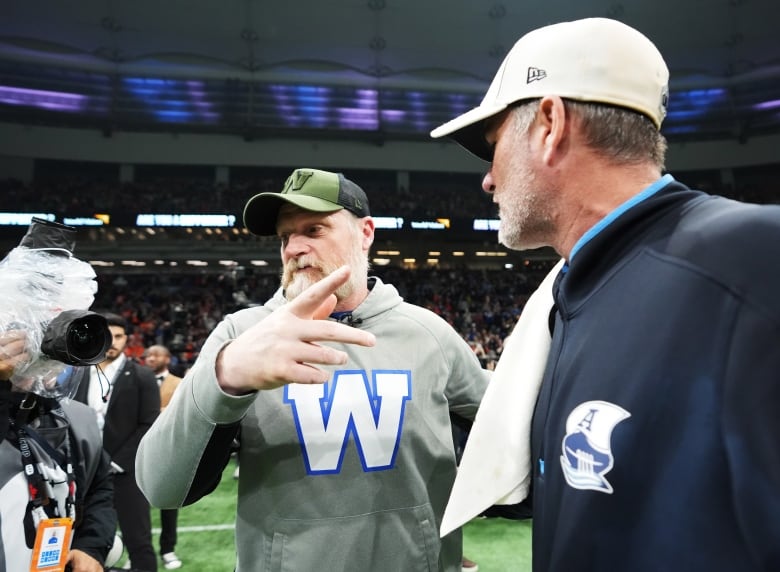 Two men stand on a football field.