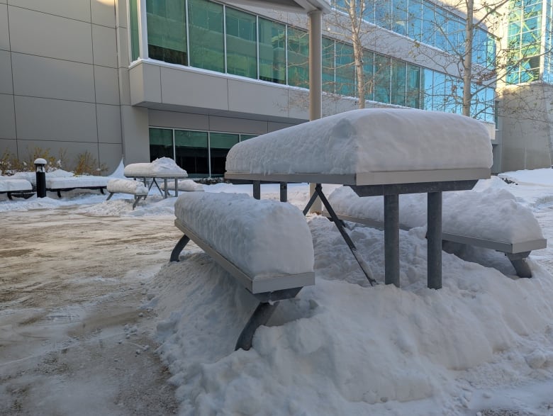 A tall pile of snow on a picnic table.