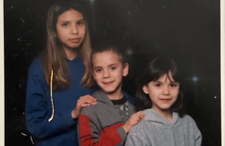 Three kids of varying heights pose for a photo together.