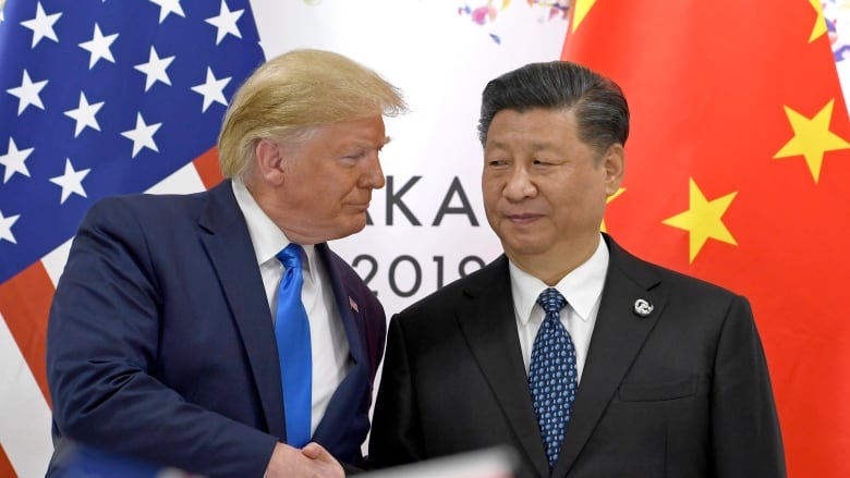 An older cleanshaven Caucasian man and a man of similar age of Asian descent are shown turned to each other. Each is wearing suit and tie.