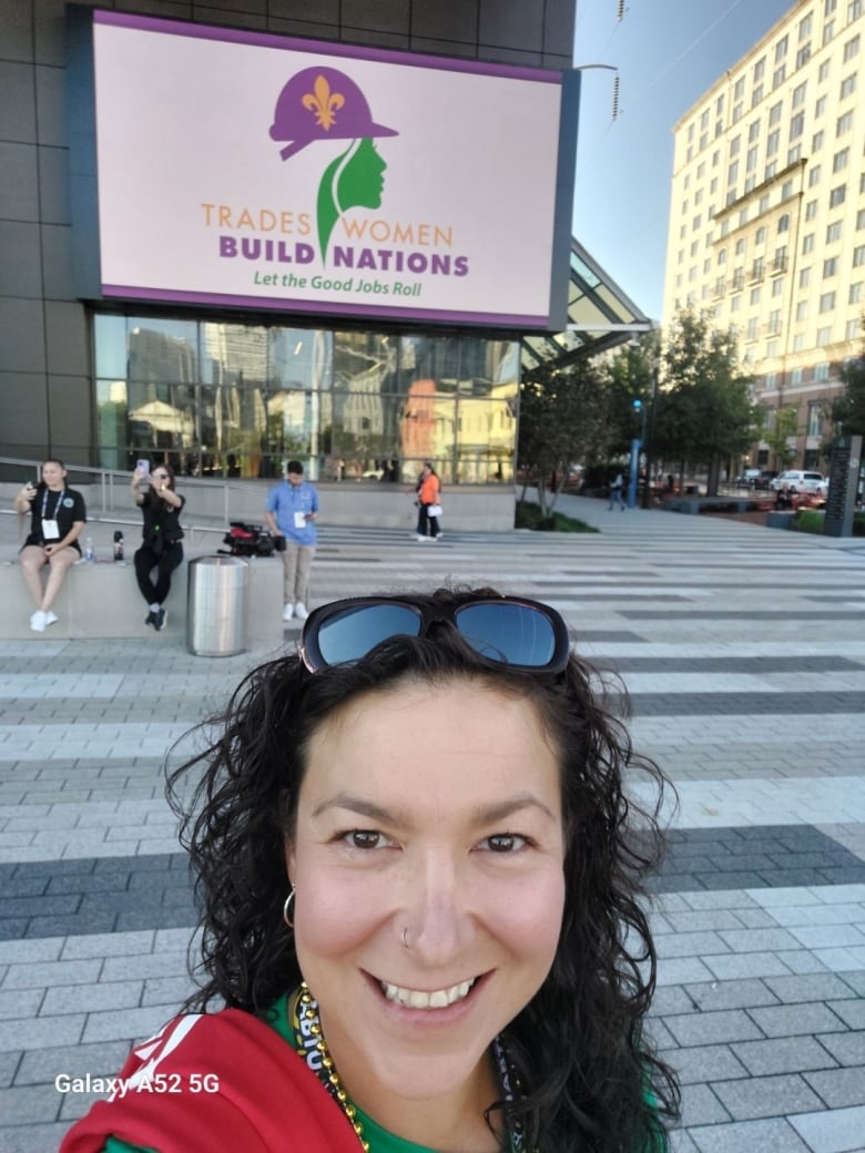 A women taking a selfie in front of a building that says 